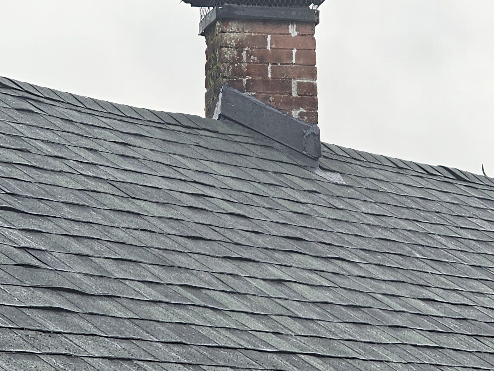 New architectural shingle roof by J&Y Roofing with freshly flashed brick chimney