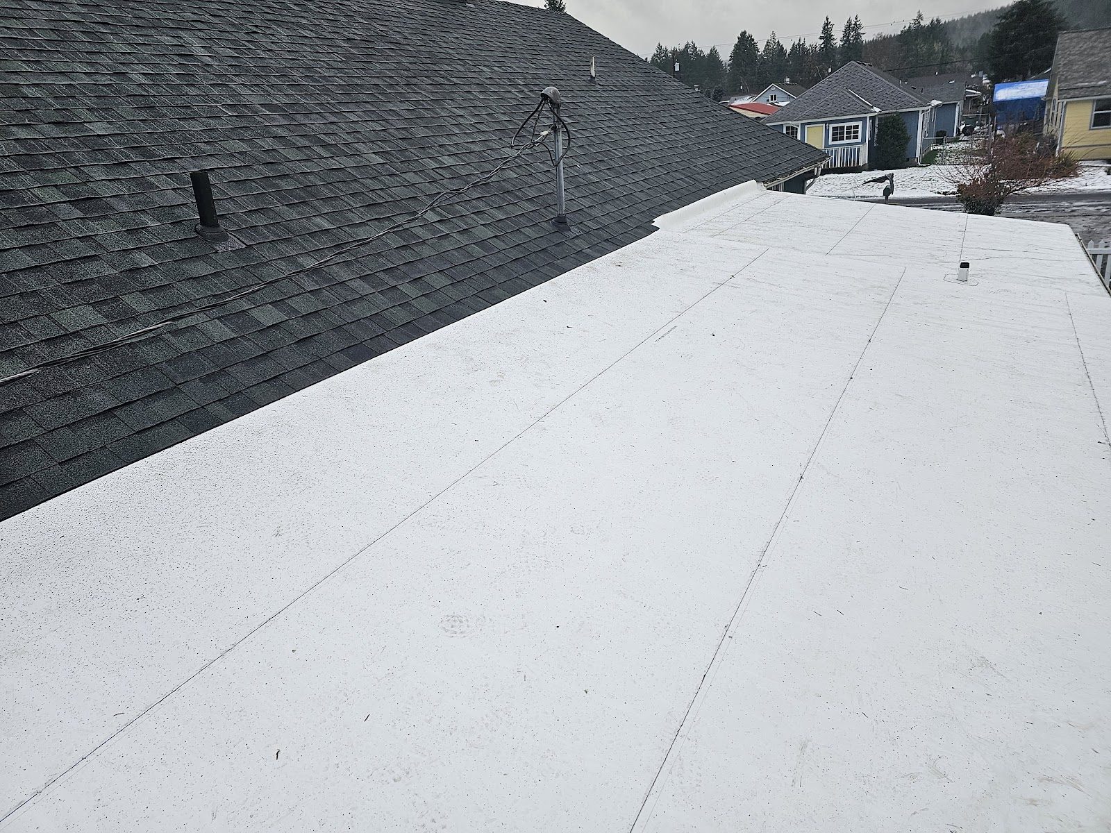 White TPO membrane flat roof meeting an architectural shingle roof