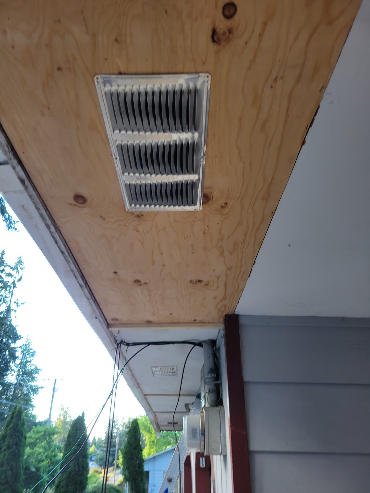 Rebuilt soffit with new plywood and vent under a roof eave